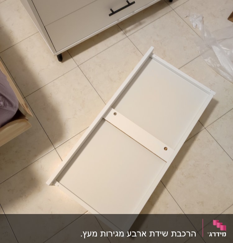 חלקי מגירה מפורקים על רצפת קרמיקה